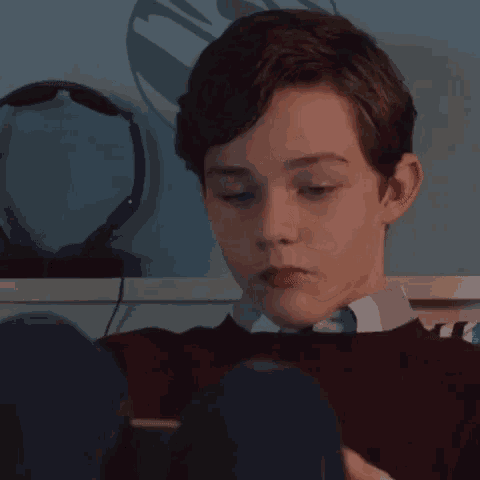 a young boy is sitting on a bed using a tablet computer .