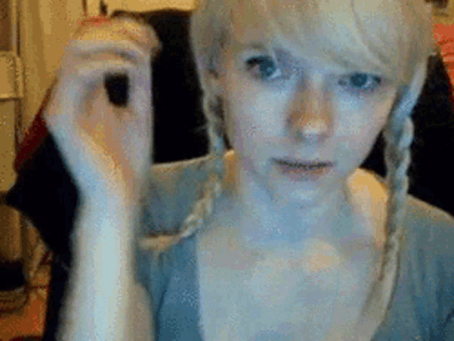 a girl with blonde hair and pigtails is making a funny face
