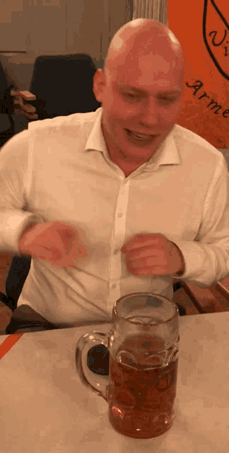 a man is sitting at a table with a mug of beer in front of him