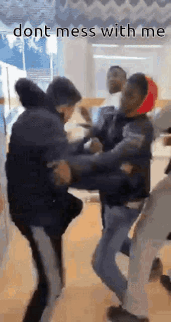 a group of young men are fighting in a room with the words `` dont mess with me '' written on the bottom .