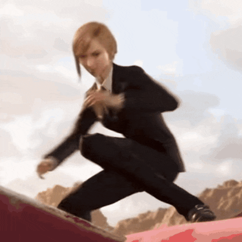 a woman in a suit is kneeling down on a red surface