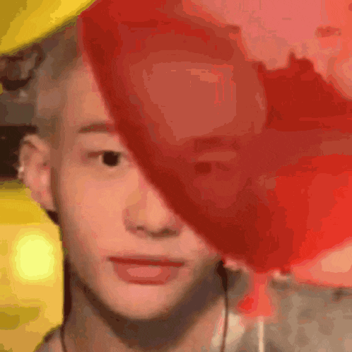 a close up of a person 's face with a red balloon covering half of it .