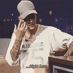 a man wearing a hat is talking on a cell phone and says `` right here '' .
