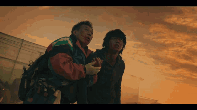 a man with blood on his face stands next to another man with blood on his face