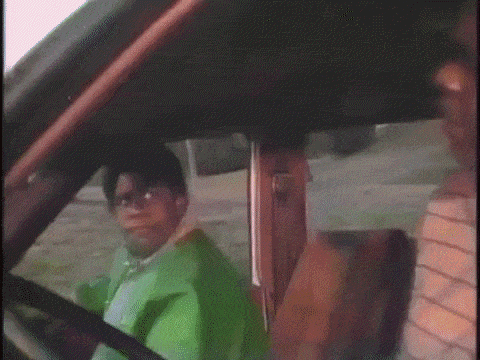 a person in a green jacket is driving a car