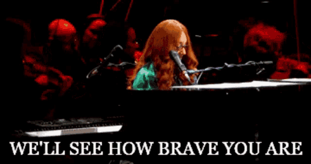 a woman singing into a microphone with the words we 'll see how brave you are behind her