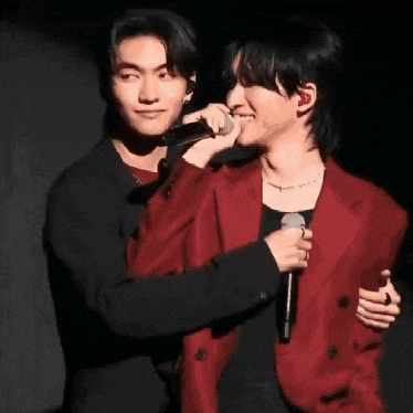 a man in a red jacket is hugging another man in a black jacket .