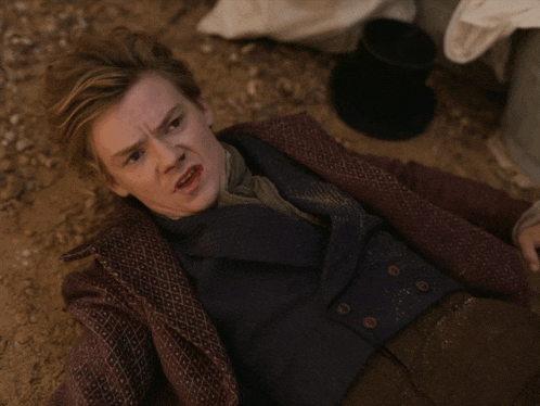 a man in a suit is laying on the ground and making a funny face