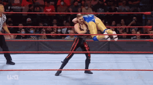 a wrestler is being lifted in the air by another wrestler during a wrestling match