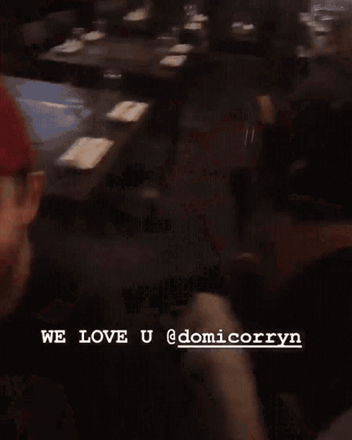 a blurred image of a person sitting at a table with the words we love u @domicorryn