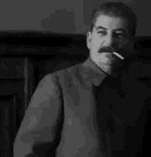 a black and white photo of a man smoking a cigarette .