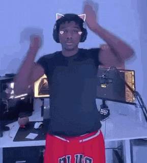 a man wearing headphones and red shorts is dancing in front of a microphone .