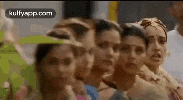 a group of women are standing next to each other in a row .