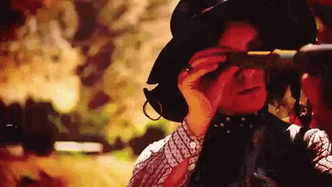a man in a hat looks through a telescope