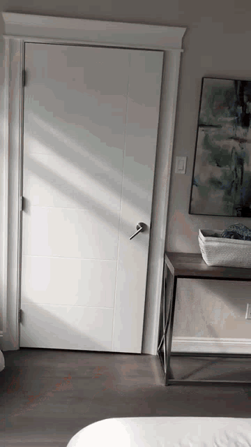 a white door is open in a bedroom with a painting on the wall above it