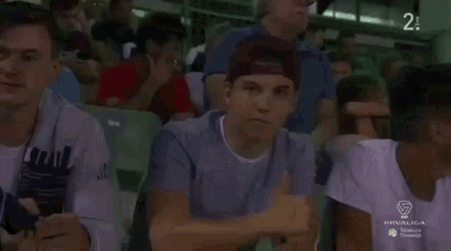 a group of young men are sitting in a stadium watching a game with the number 2 on the screen
