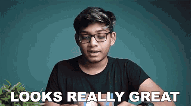 a young man wearing glasses and a black shirt is making a funny face and saying `` looks really great '' .