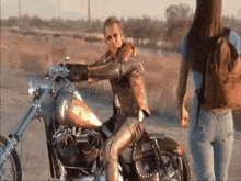 a woman is sitting on a motorcycle while another woman stands next to her .
