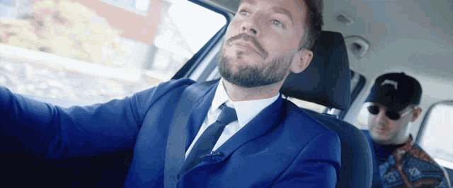 a man in a blue suit driving a car