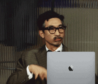 a man with glasses and a mustache is holding an apple laptop