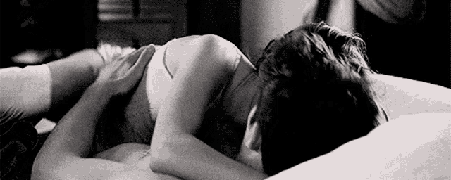 a man and a woman are laying on a bed hugging and kissing .
