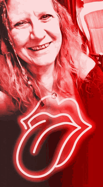 a woman is smiling in front of a neon sign that says rolling stones