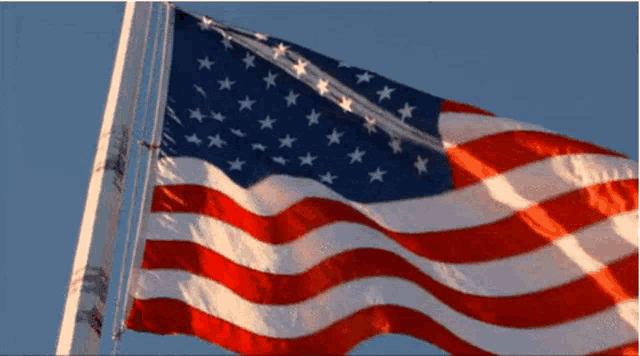 an american flag is waving in the wind with a blue sky in the background