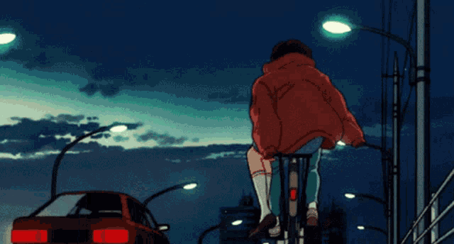 a man in a red hoodie is riding a bike in front of a truck with the letter t on the front