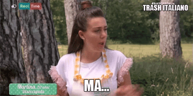 a woman wearing a necklace that says ma is standing in front of trees