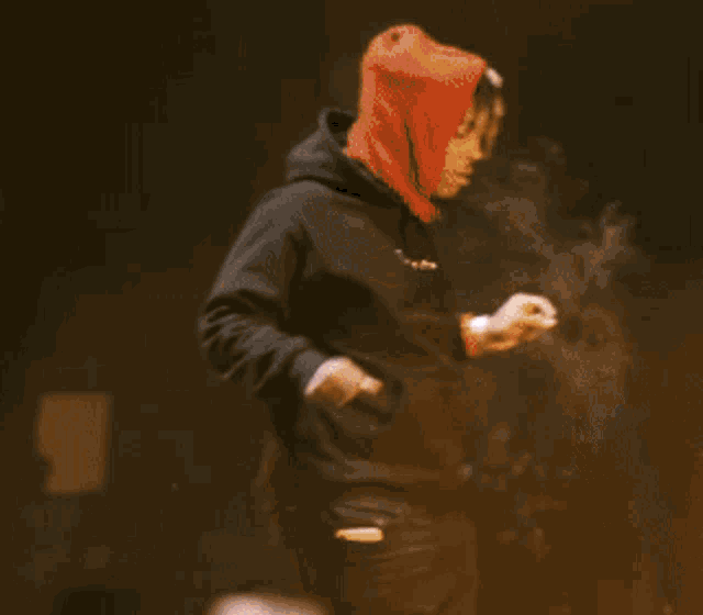 a man in a red hooded jacket is standing in front of a camera