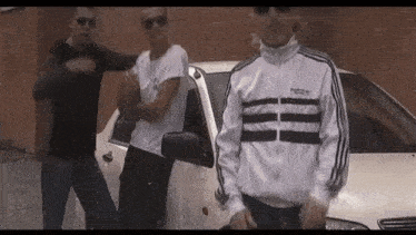 a group of young men are standing next to a car .