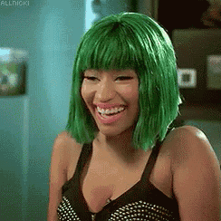 the woman is wearing a green wig and smiling .