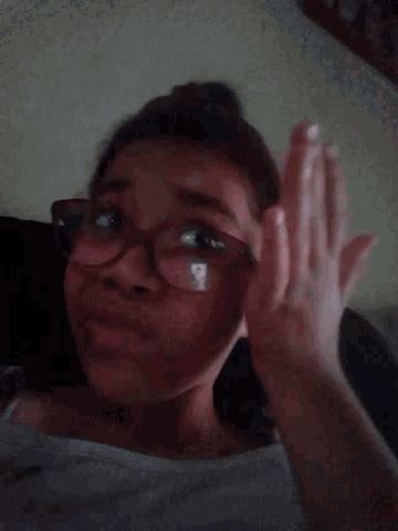 a woman wearing pink glasses looks down at something
