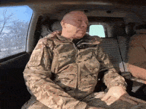 a man in a camouflage jacket is sitting in the back of a car