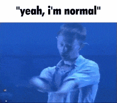 a man in a white shirt says " yeah i 'm normal " in front of a blue background