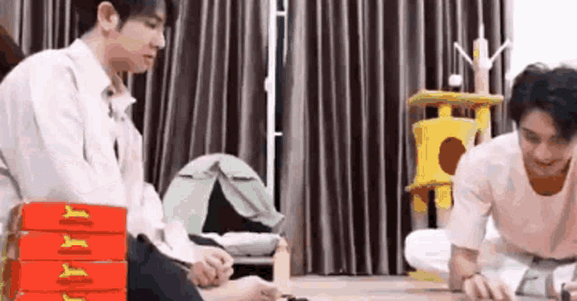 a couple of men are sitting on the floor in a living room playing a game .