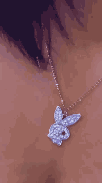 a close up of a woman wearing a necklace with a playboy bunny pendant