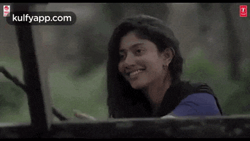 a woman is smiling while sitting in the back of a truck .