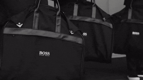 a black and white photo of a person carrying a bag that says boss on it