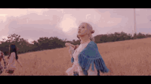 a woman with pink hair is standing in a field holding a feather .