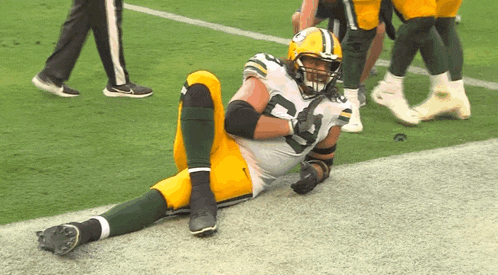 a football player is laying on the field with his legs crossed