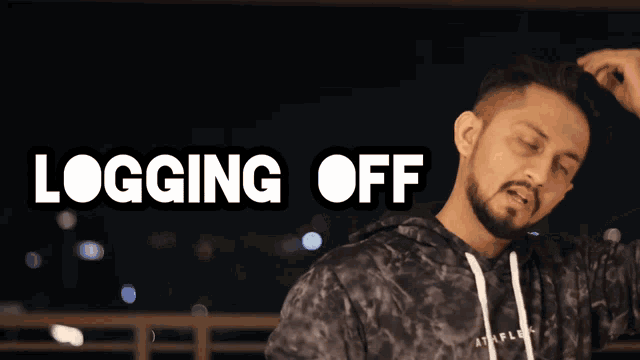 a man in a black hoodie is standing in front of a sign that says logging off
