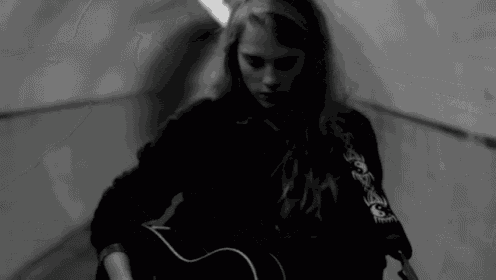 a black and white photo of a girl holding a guitar