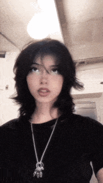 a woman wearing a black shirt and a silver necklace with skulls on it