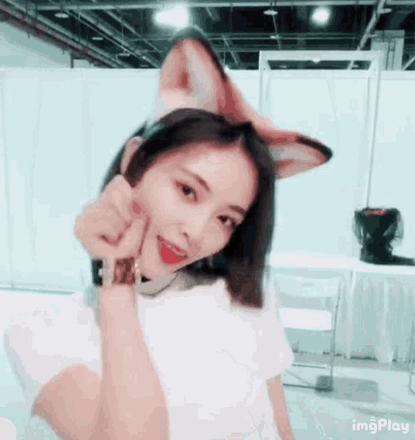 a woman wearing a headband with fox ears is giving a peace sign