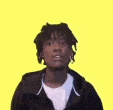 a man with dreadlocks is wearing a black jacket and a white t-shirt .