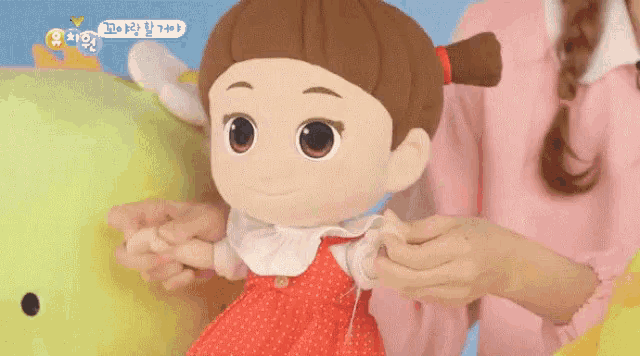 a person is holding a stuffed doll with korean writing on the bottom right