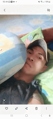 a man is laying on a bed with his head on a pillow and his hat on