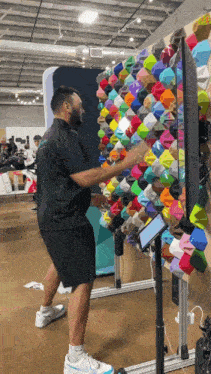 a man in a black shirt is standing in front of a wall covered in colorful socks