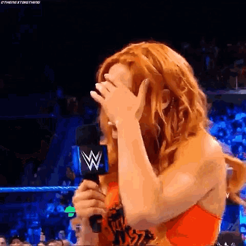 a woman is covering her face while holding a microphone .